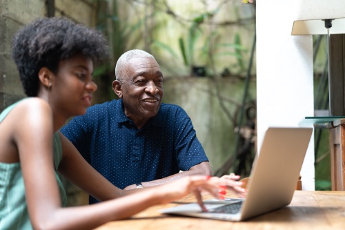 A woman and her dad browse a laptop computer together